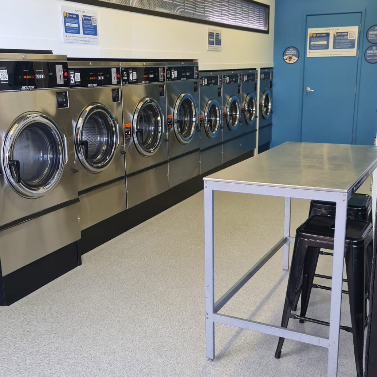 Photo of table and row of washing machines from angle